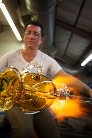 Latino glass artist sculpting glass vase with blowtorch