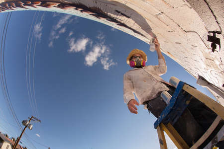 Wide angle view of disguised graffiti artist working on muralの写真素材