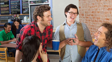 Happy group of young people laughing in cafe