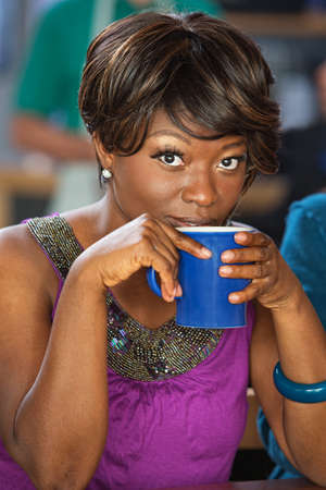 Pretty African woman sipping from coffee mugの写真素材