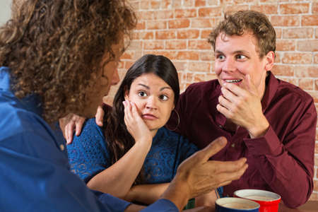 Fascinated friends listening to man in cafeの写真素材