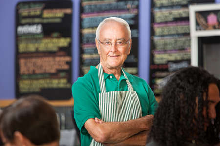 Independent older cafe employee with striped apronの写真素材