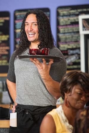Happy Native American cafe owner serving drinks to customersの写真素材