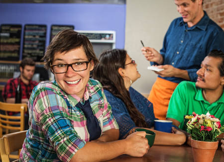 Cheerful young white female with friends in coffee houseの写真素材