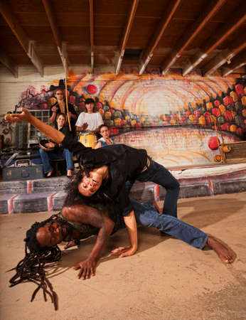 Hispanic capoeira experts bending and twisting their bodiesの写真素材