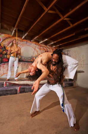Capoeira performer holding partner in back bending over shouldersの写真素材