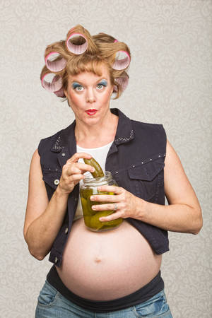 Pregnant white woman in curlers with jar of picklesの写真素材