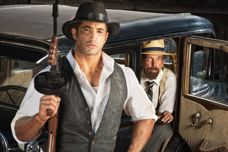 Cute 1920s gangster with submachine gun and partner in carの写真素材