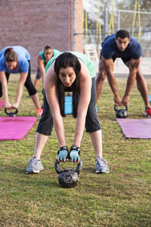 Beautiful woman leading group with kettle bell weights