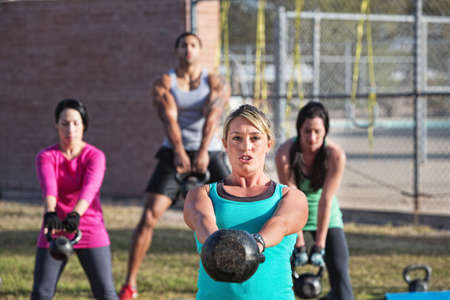 Fit woman leading group of adults with weights