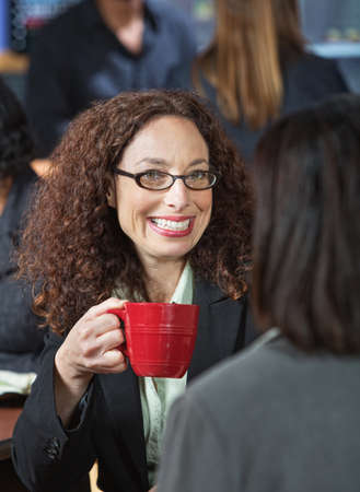 Cheerful business woman with cup and friendの写真素材