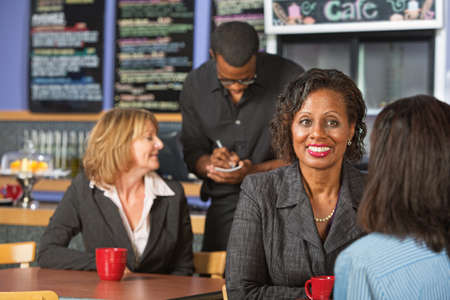 Mature smiling business woman with friend in cafeの写真素材