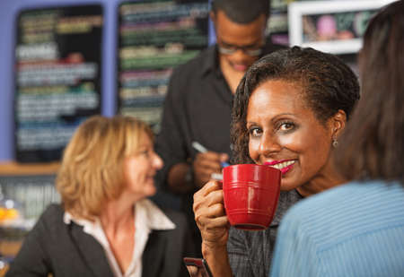 Cheerful business woman sipping beverage in cafeの写真素材