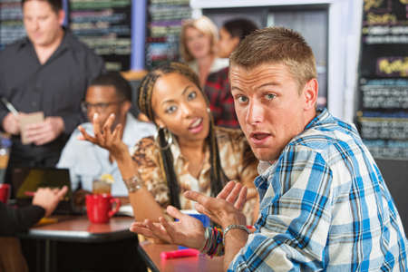 Bickering young married couple sitting in coffee houseの写真素材