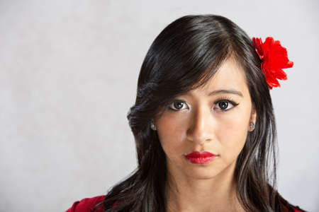 Calm beautiful Asian female with red flowerの写真素材