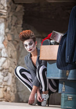 Cute female comedia del arte performer next to luggageの写真素材