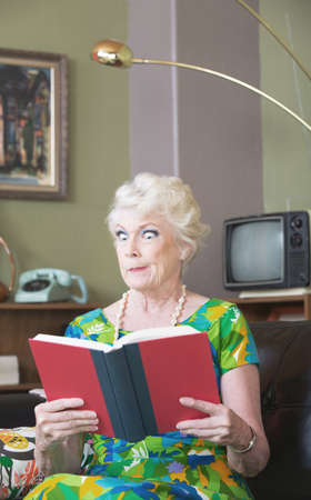 Single skeptical woman in green reading a bookの写真素材