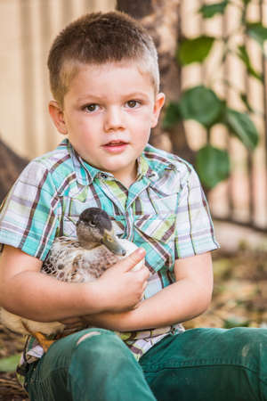 Cute child in green holding his pet duckの写真素材