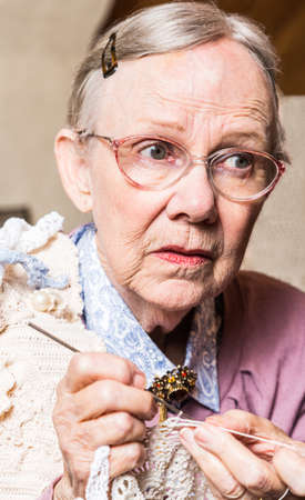 Old woman crocheting with worried expressionの写真素材
