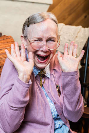 Happy old woman with a hands up gestureの写真素材