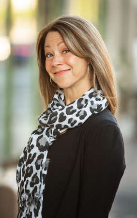 Upbeat smiling beautiful woman with scarf in urban sceneの写真素材