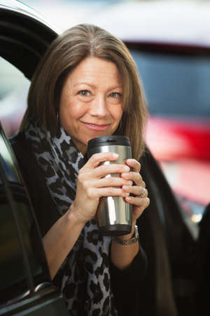 Cheerful mature adult woman holding coffee thermosの写真素材
