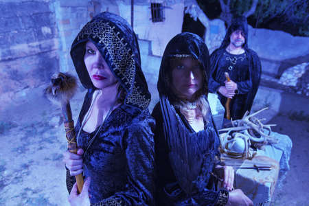 Group of three witches in black robes near altar outdoorsの写真素材
