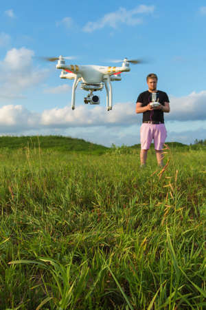 Single man in pink pants controlling drone outdoorsの写真素材