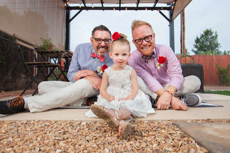 Happy same sex couple sitting with daughter outdoorsの写真素材