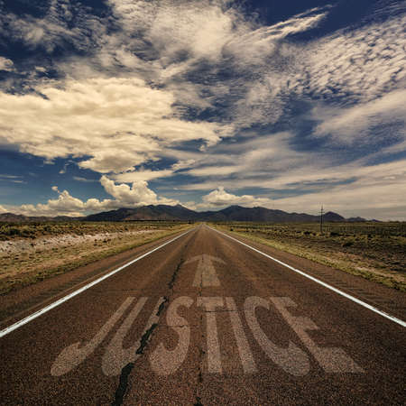Image of the word justice painted on a desert highwayの写真素材