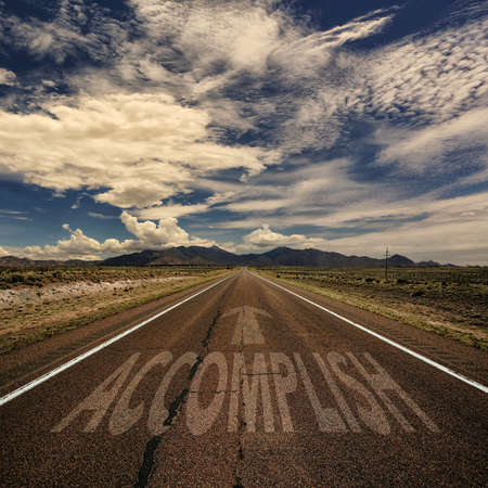 Conceptual image of desert road with the word accomplish and arrowの写真素材