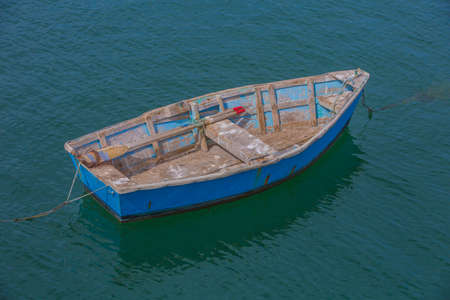 Colorful weathered rowboat anchored in shallow ocean waterの写真素材