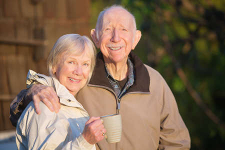Confident white senior citizen couple outdoors with coffeeの写真素材