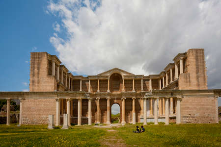 Couple seated near of gymnasium ruins at Sardis in Turkeyの写真素材