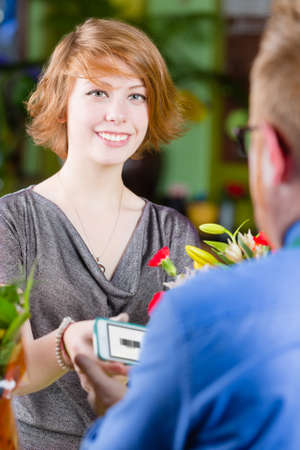Teen customer in a busy flower shop using electronic couponの写真素材