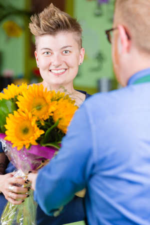 Pretty woman buying sunflowers at a florist shopの写真素材