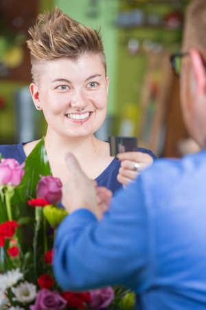 Cute female customer in flower shop using creditの写真素材