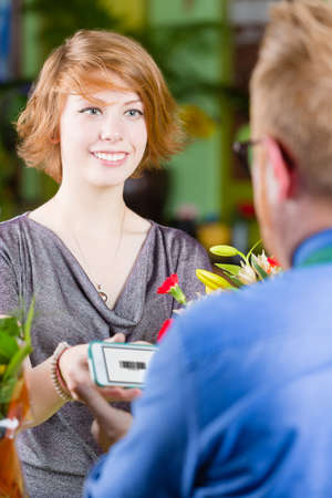 Smiling customer in a busy flower shop using electronic couponの写真素材