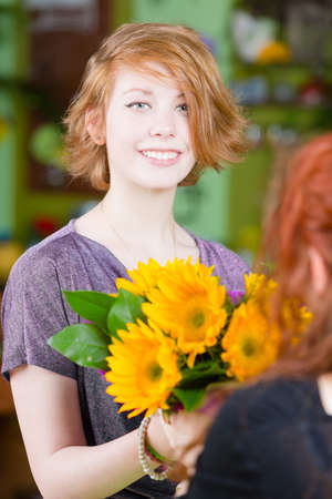 Teenage girl buying sunflowers at a florist shopの写真素材
