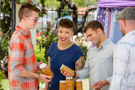 Attractive couple purchases honey at outdoor farmers marketの写真素材