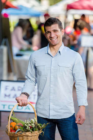 Smiling man with basket of produce at farmers marketの写真素材