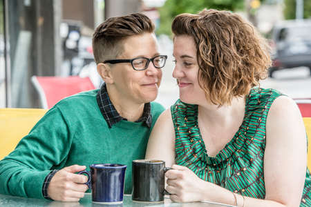 Joyful lesbian couple looking at each other while seated outsideの写真素材