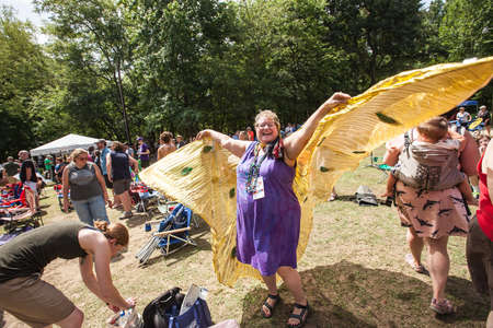 HOT SPRINGS, NC - JULY 10: Joyful woman in purple dress flying with bird wings at the Wild Goose Festival on July 10, 2016 in Hot Springs, NC, USA.のeditorial素材