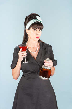 Sultry retro woman in black dress with Cosmopolitan and decanterの写真素材