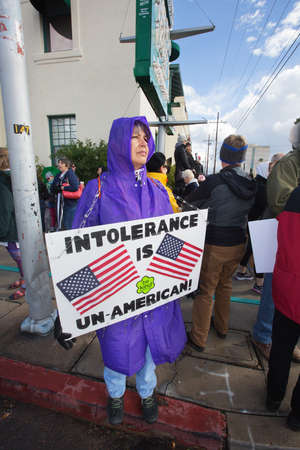 TUCSON, AZ - JANUARY 21: Protestor wearing raincoat while holding poster about tolerance at the Women's March on Washington January 21, 2017 in Tucson, AZ, USA.のeditorial素材