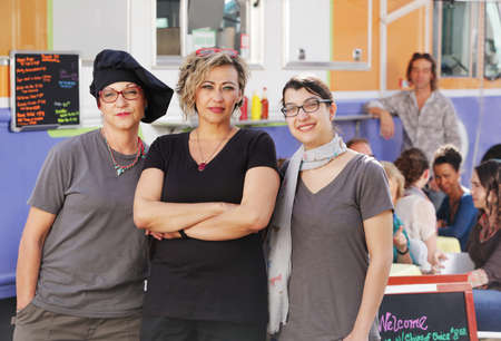 Three food workers posing in front of an outdoor food truckの写真素材