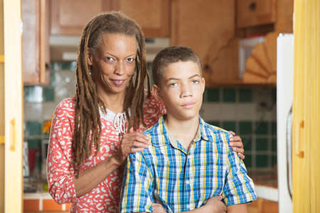 African-American mother and her frustrated teenaged son stand together in kitchenの写真素材