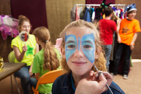 Close up view of girl getting her face painted while seated in a dressing roomの写真素材