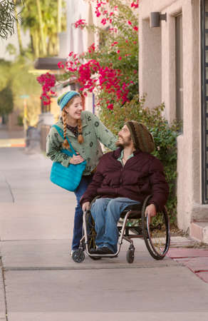Woman with friend in wheelchair laughingの写真素材