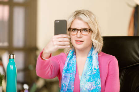 Pretty professional woman communicating or taking slefie with smart phoneの写真素材